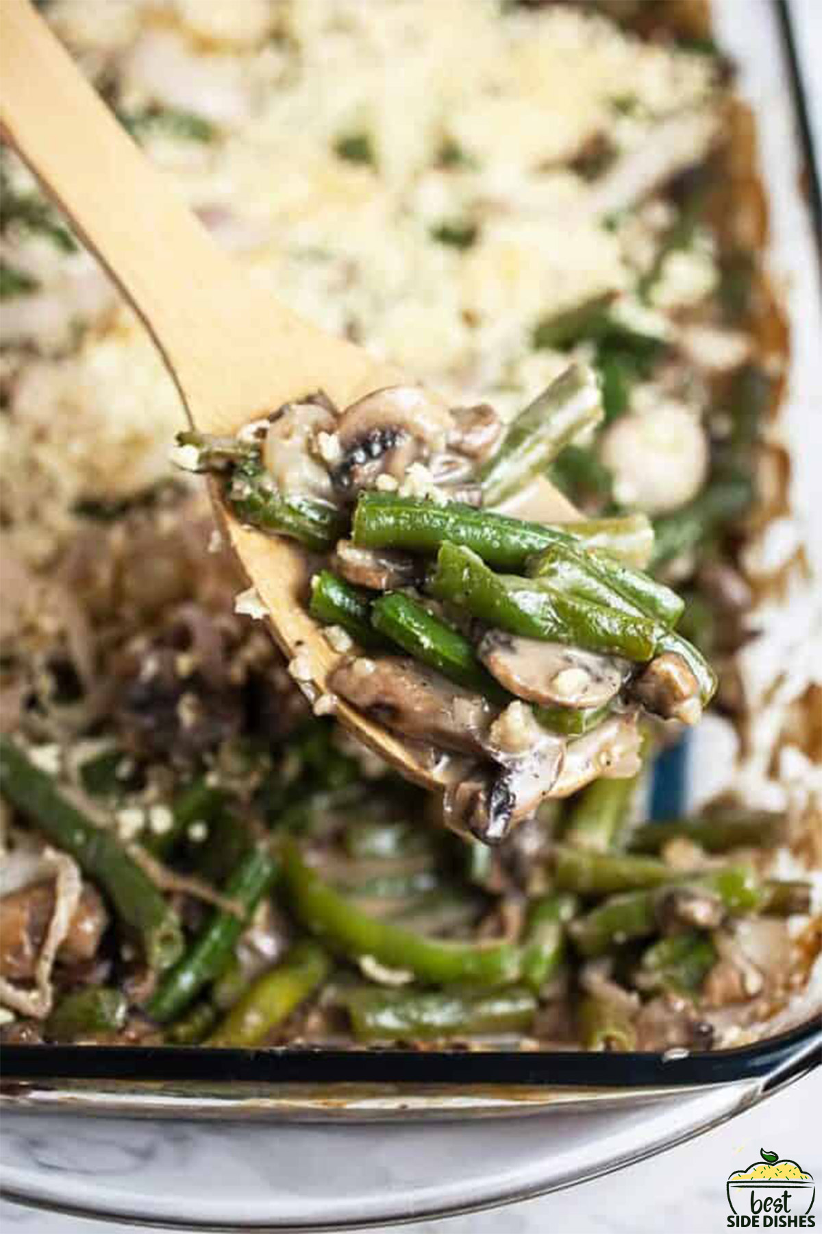 Green bean casserole in a casserole dish with a wooden spoon