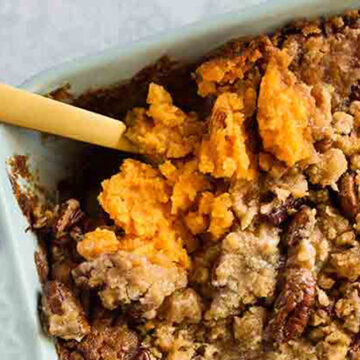 Sweet potato casserole in a dish with a wooden spoon