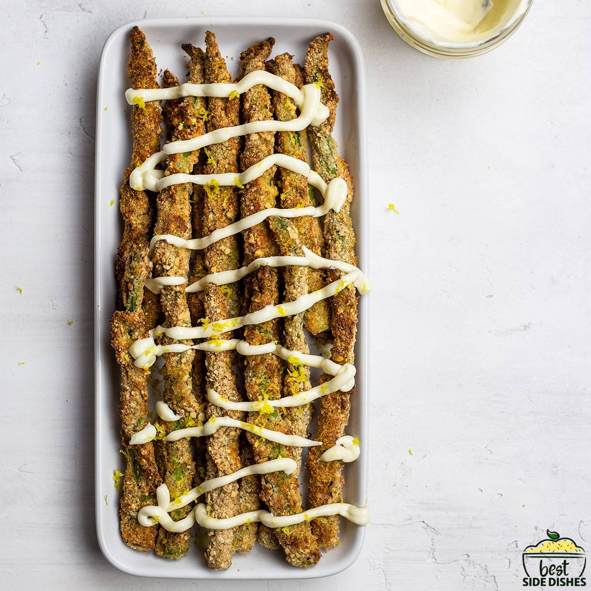 asparagus fries drizzled with aioli dip on a platter