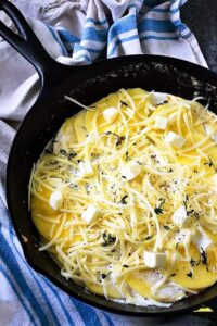 Cheese, cream, and potatoes in a cast iron skillet