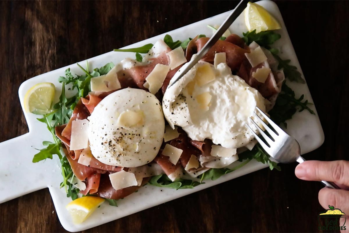 Cracking open burrata cheese on top of salad