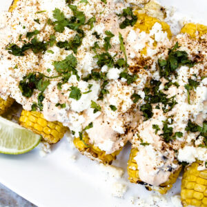 Mexican street corn on a white platter with Mexican crema