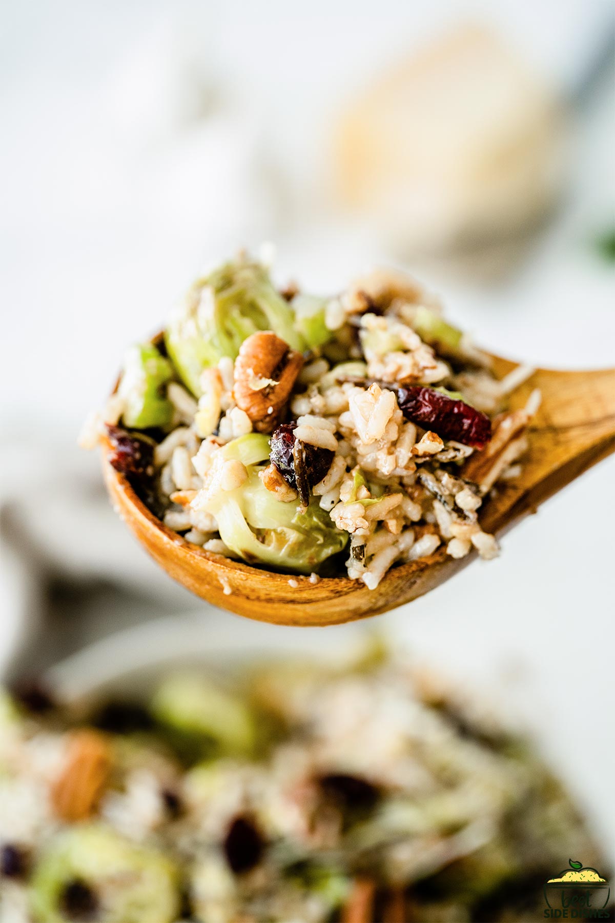 Brussels sprouts salad on a wooden spoon over a bowl of brussels sprouts