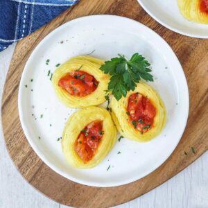 three duchess potatoes on a plate with tomato sauce
