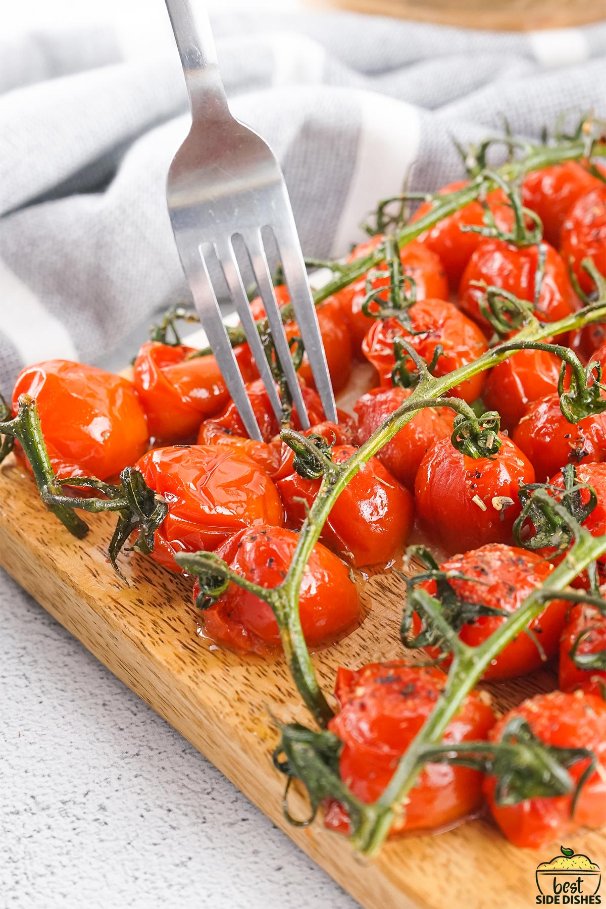 Roasted tomatoes on a board with a fork