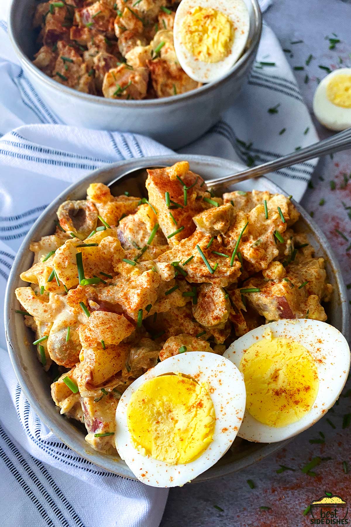 close up of potato salad with eggs and spanish seasonings in a bowl