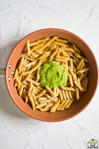 adding pea sauce to pasta in a pan