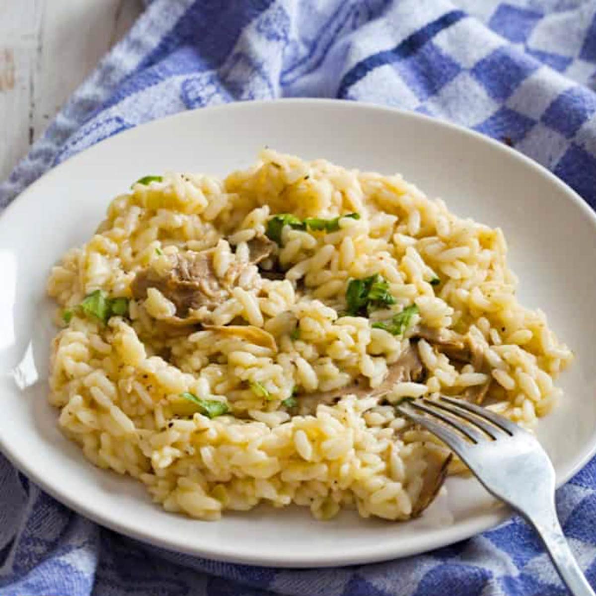 mushroom risotto on a white plate with a fork