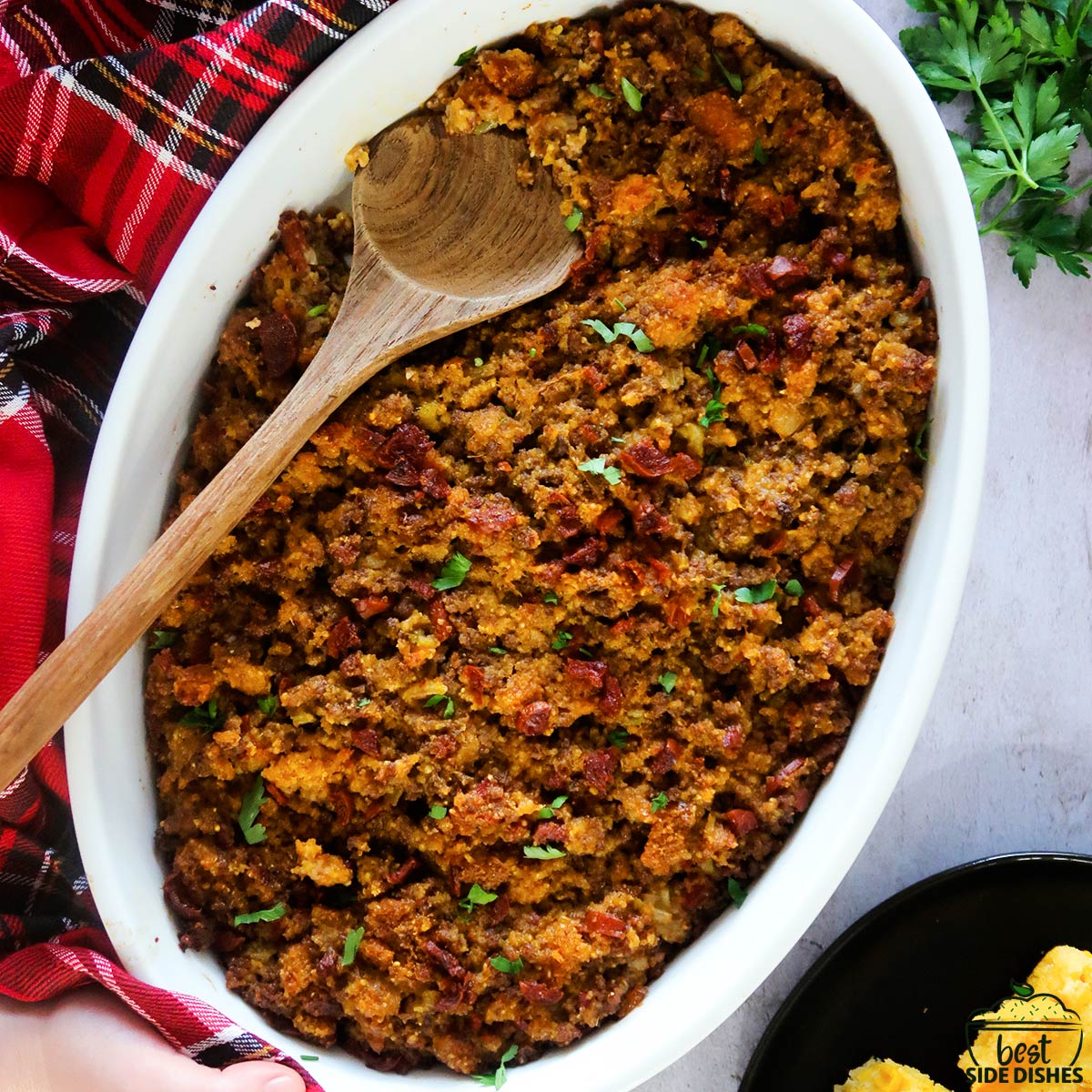 chorizo cornbread stuffing in a white dish with a wooden spoon