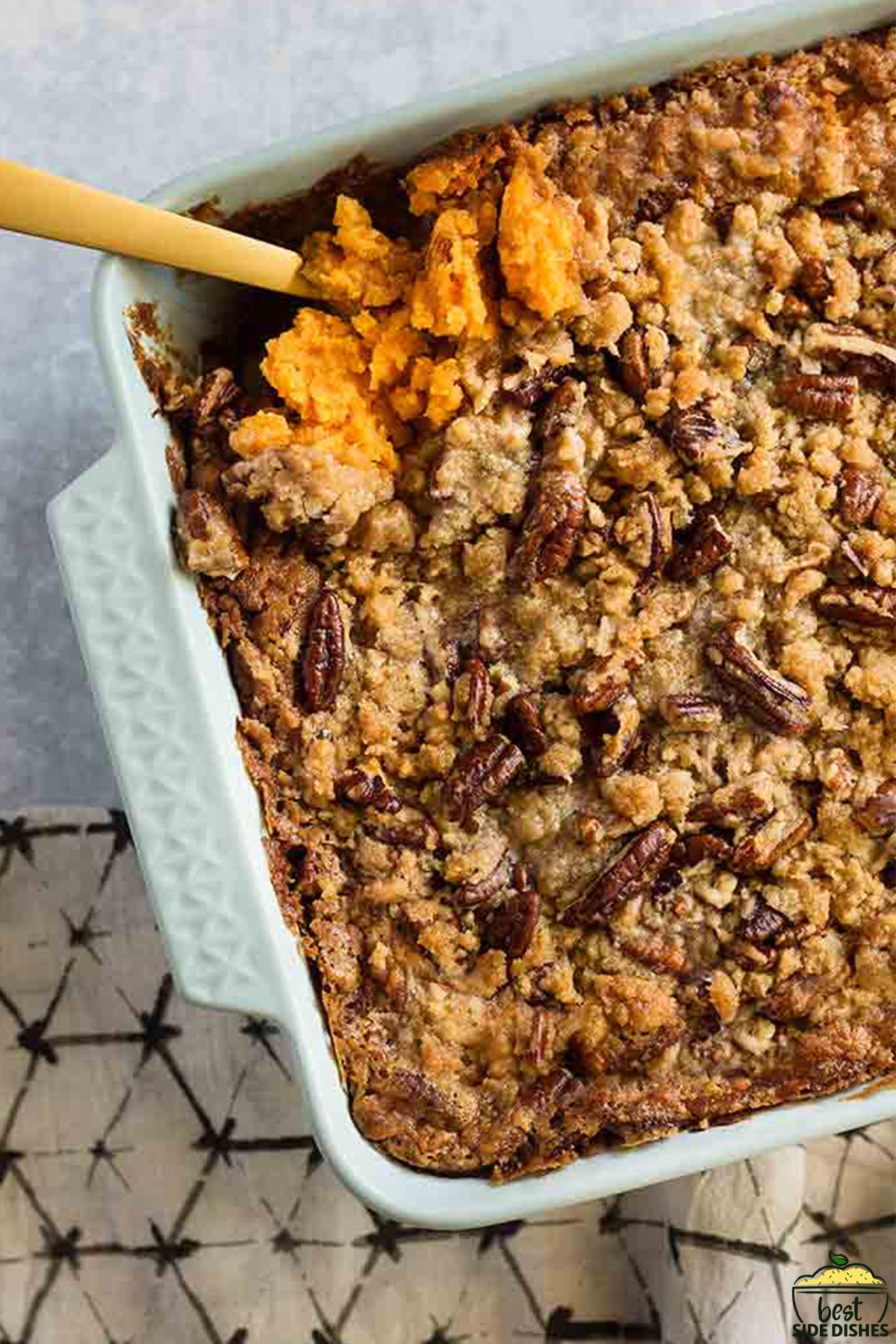 sweet potato casserole in a white dish with a wooden spoon