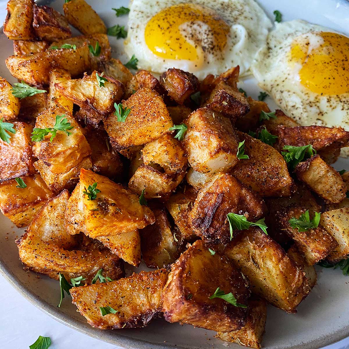 air fried potatoes on a grey plate with eggs in the background