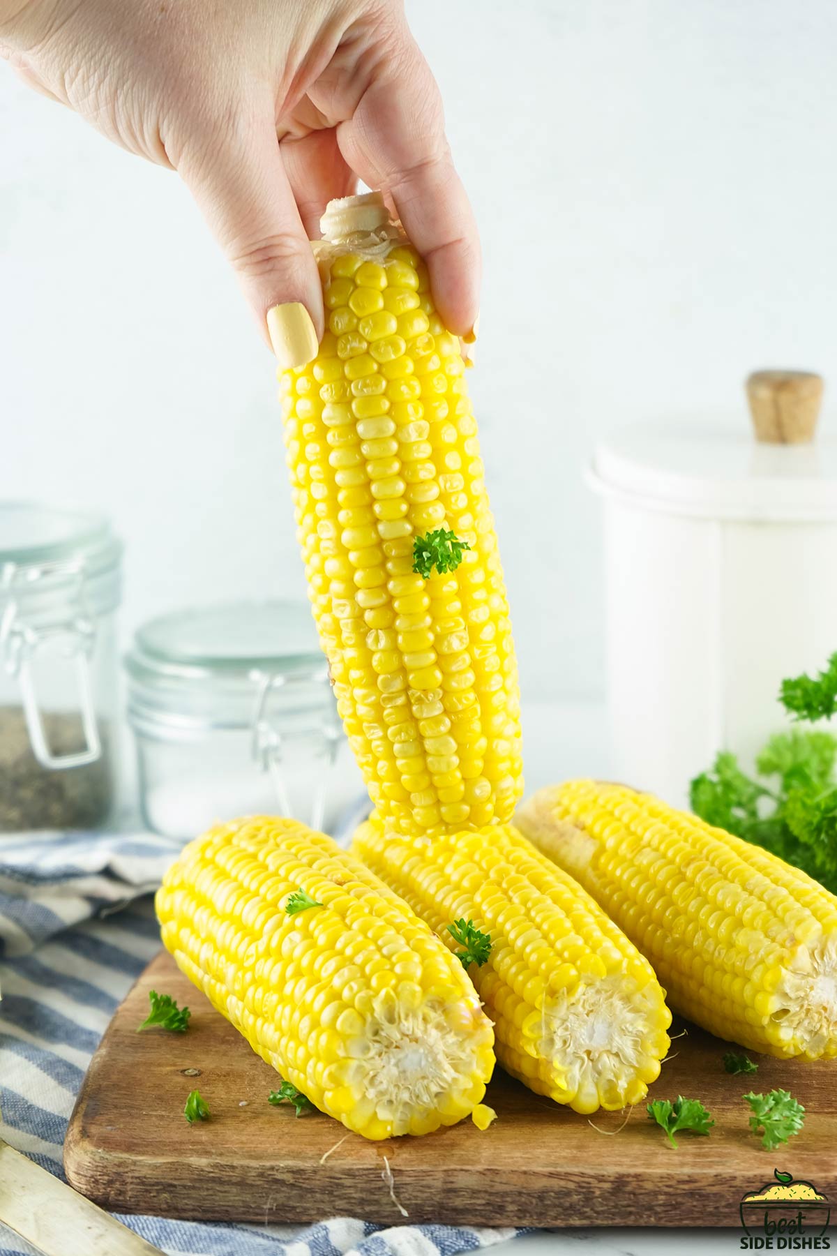 Lifting a corn on the cob from a pile of corn