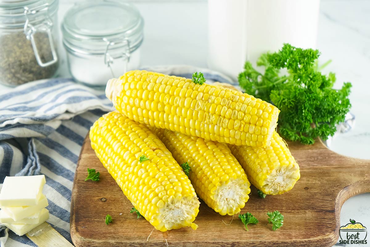 four corn on the cob on a wooden serving board