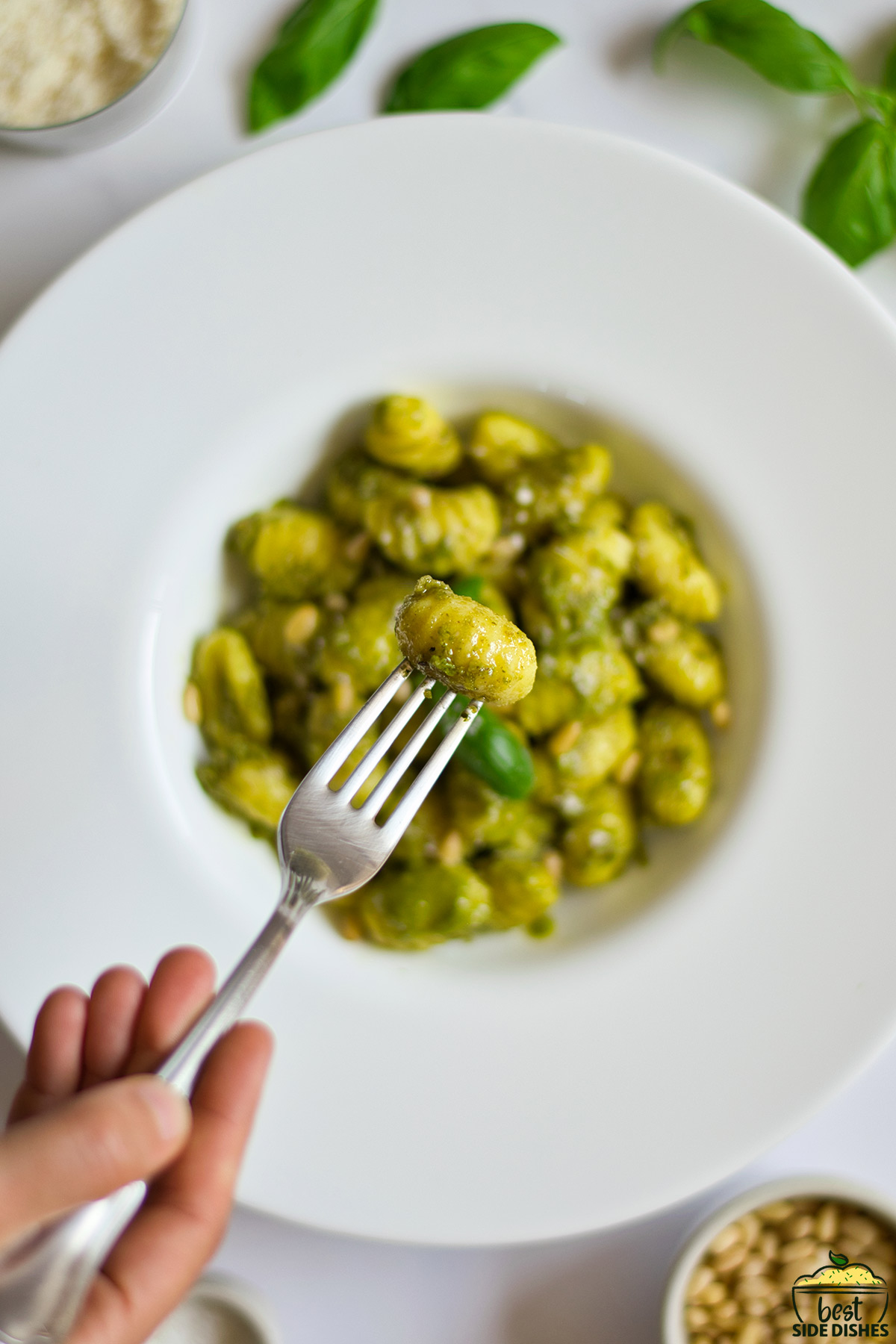 pesto gnocchi in a white plate with a fork