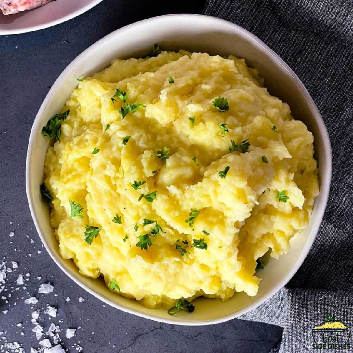 Creamy mashed potatoes piled high in a white bowl with chives on top