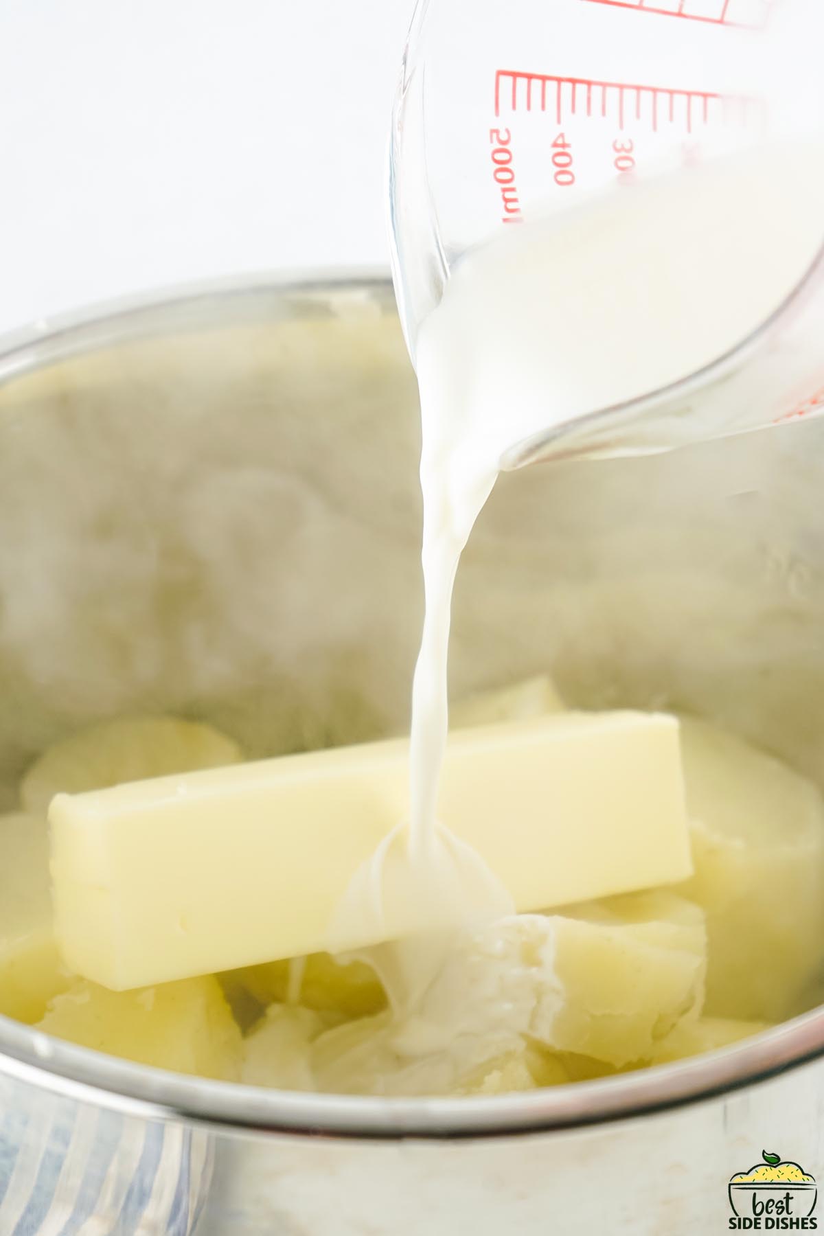 milk being poured on cooked potatoes and a stick of butter