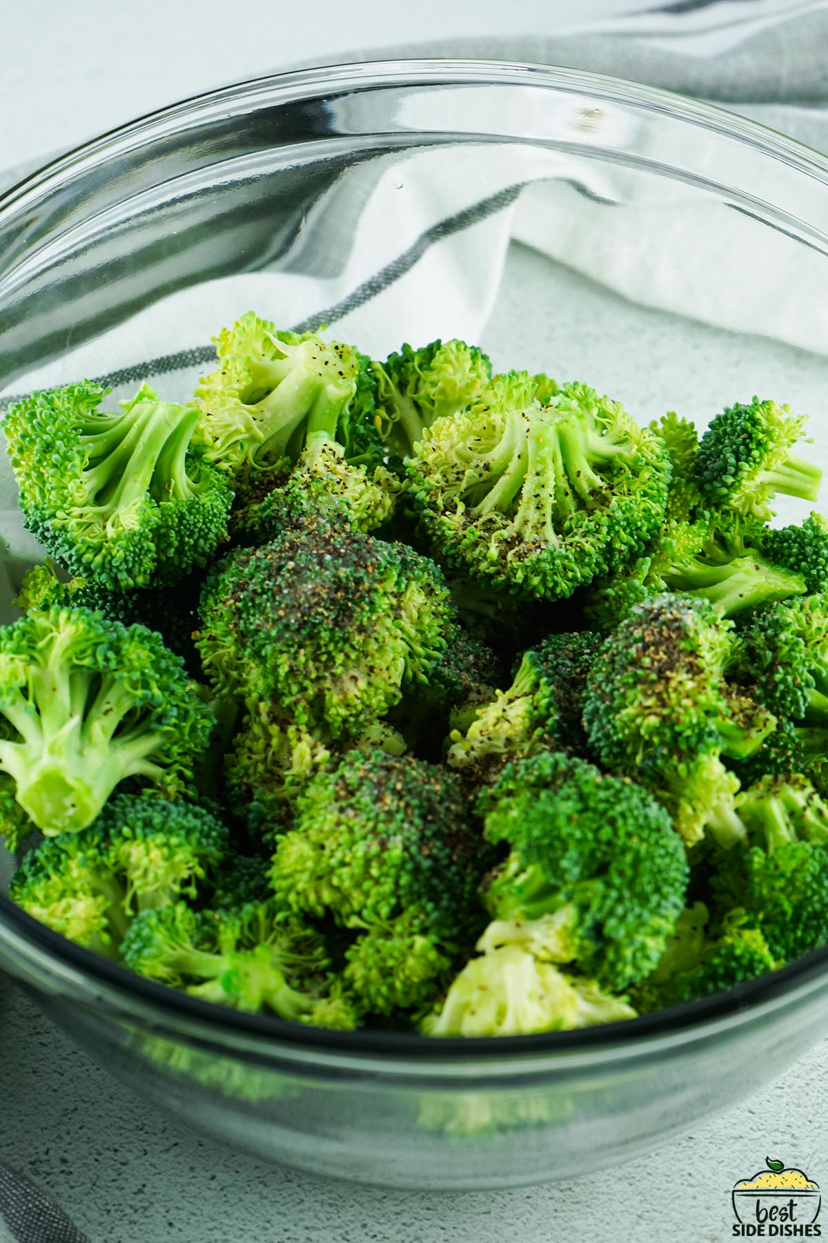 broccoli in a glass bowl with salt and pepper on top