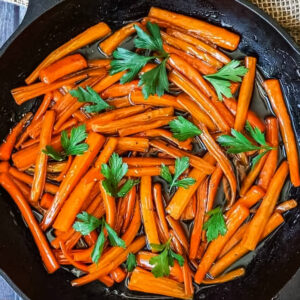 a closeup of completed maple glazed carrots in a cast iron pan