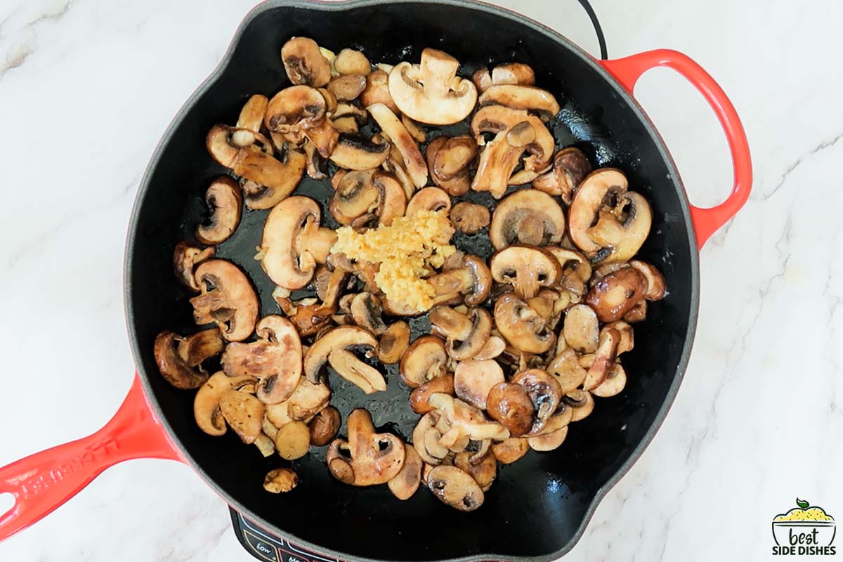 adding garlic to mushrooms in a pan