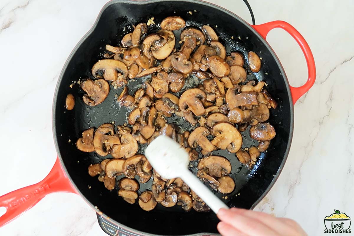 stirring mushrooms in pan to brown further